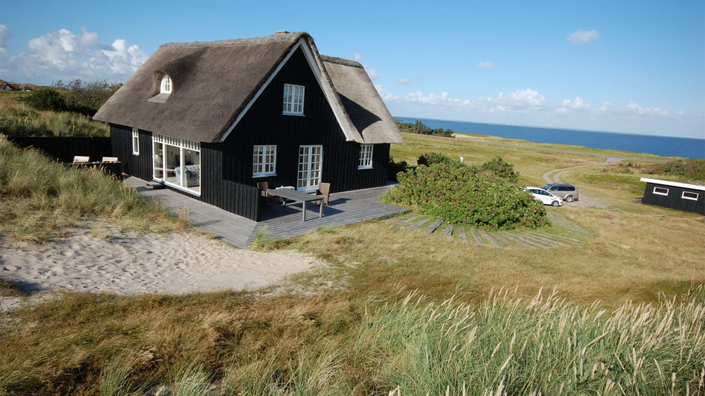 Sort feriehus med stråtag tæt på Vesterhavet