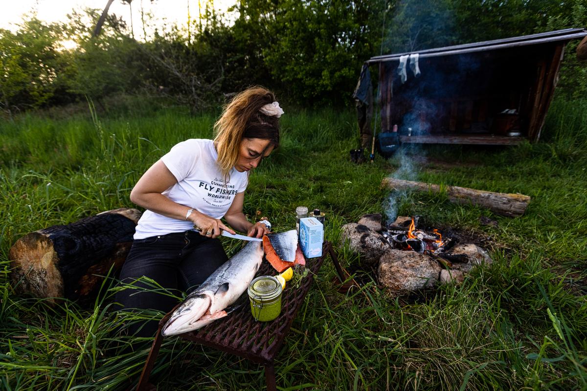 Kvinde tilbereder fisk ved bål