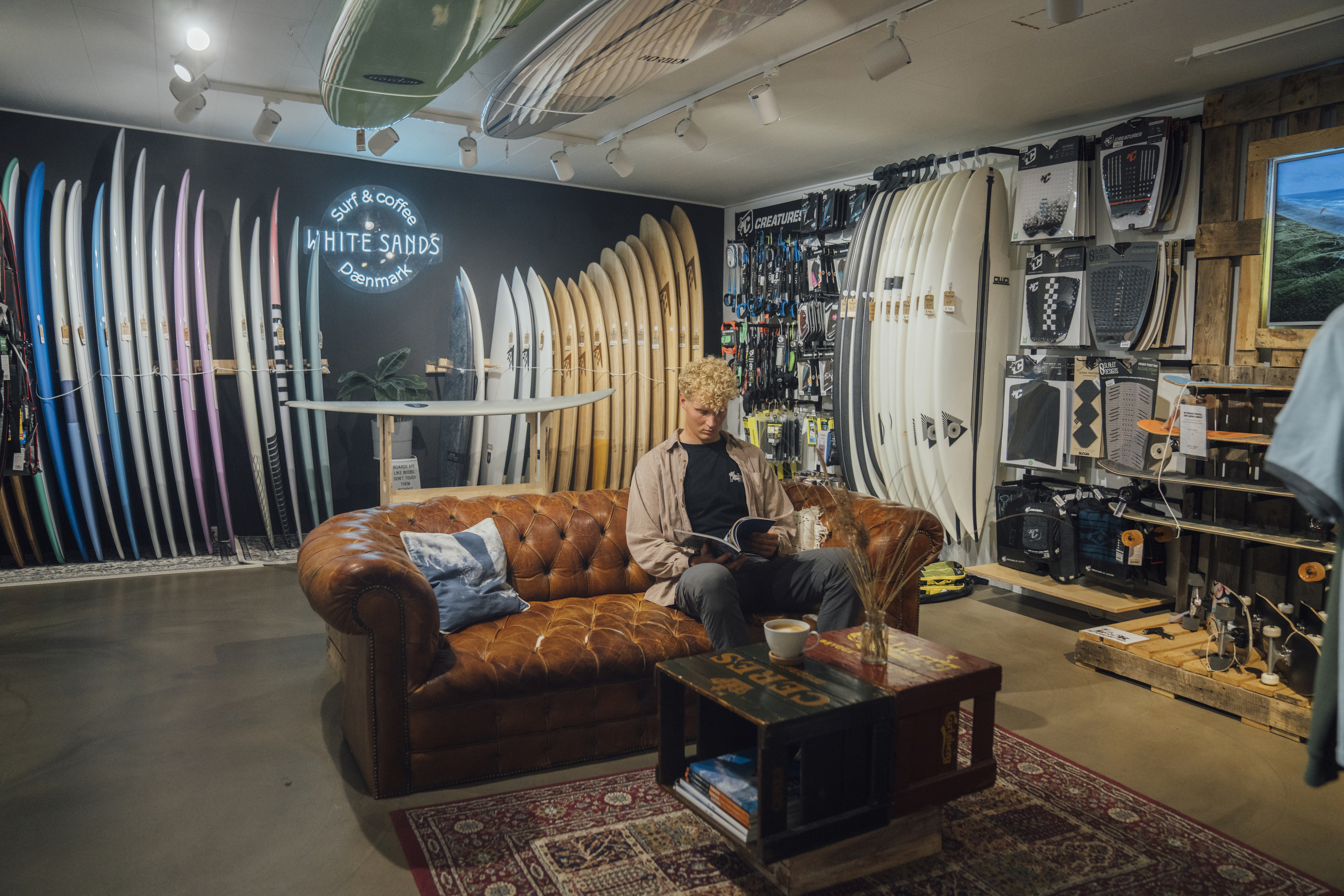 Mand sidder i surfbutik og læser magasin