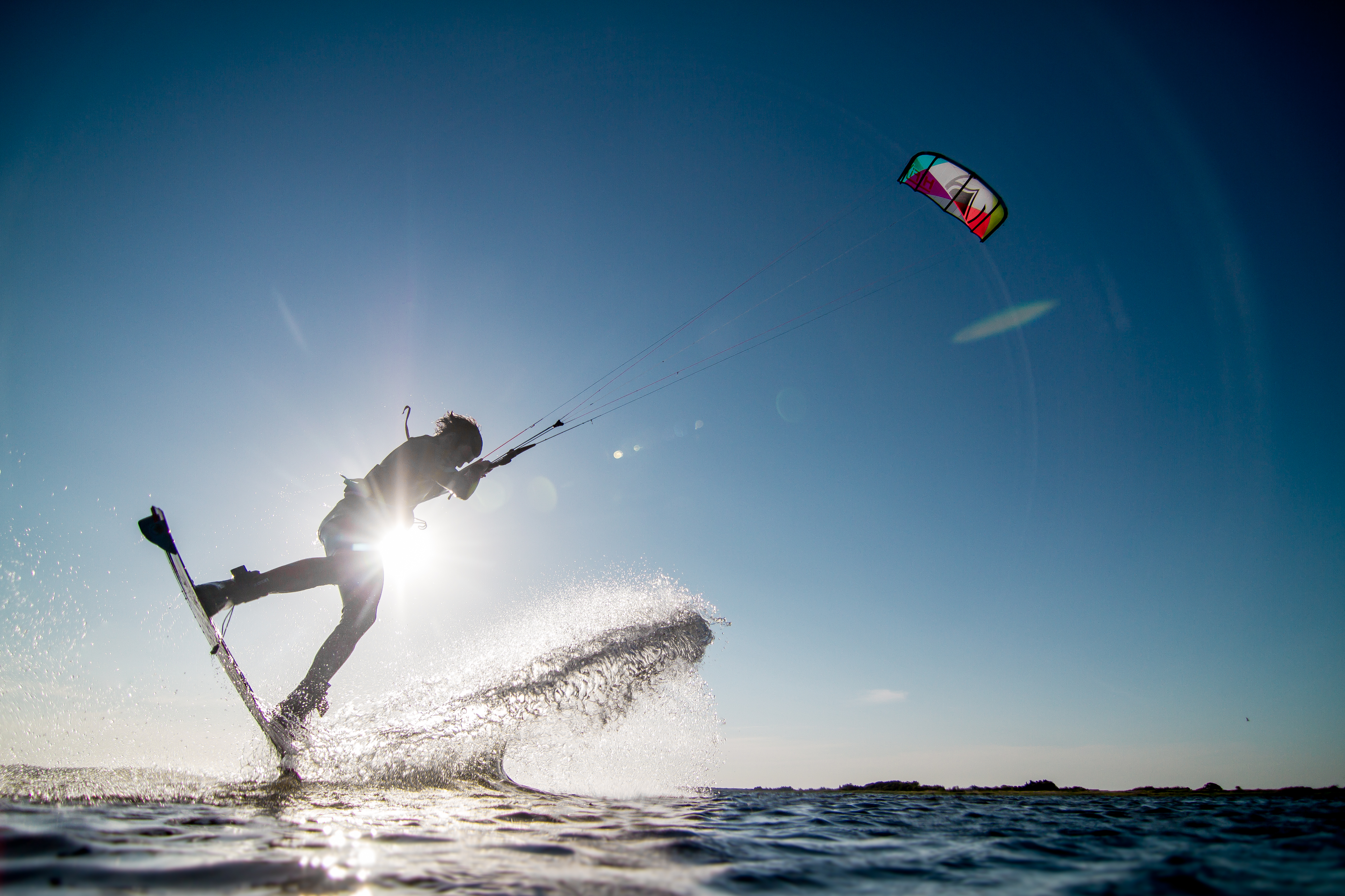 Mand kitesurfer over fjorden