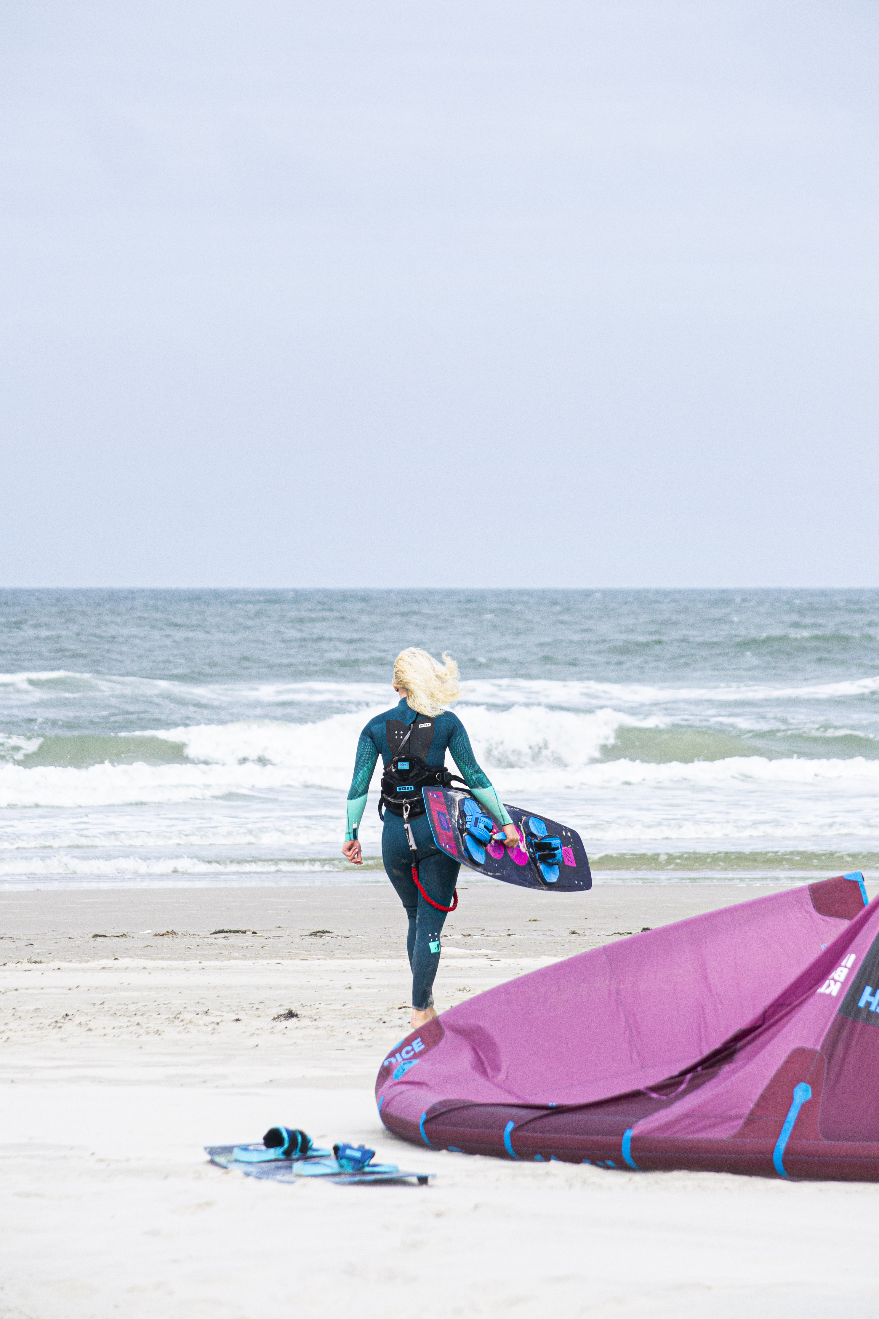 Kvinde på vej ud i vandet med hendes surfbræt