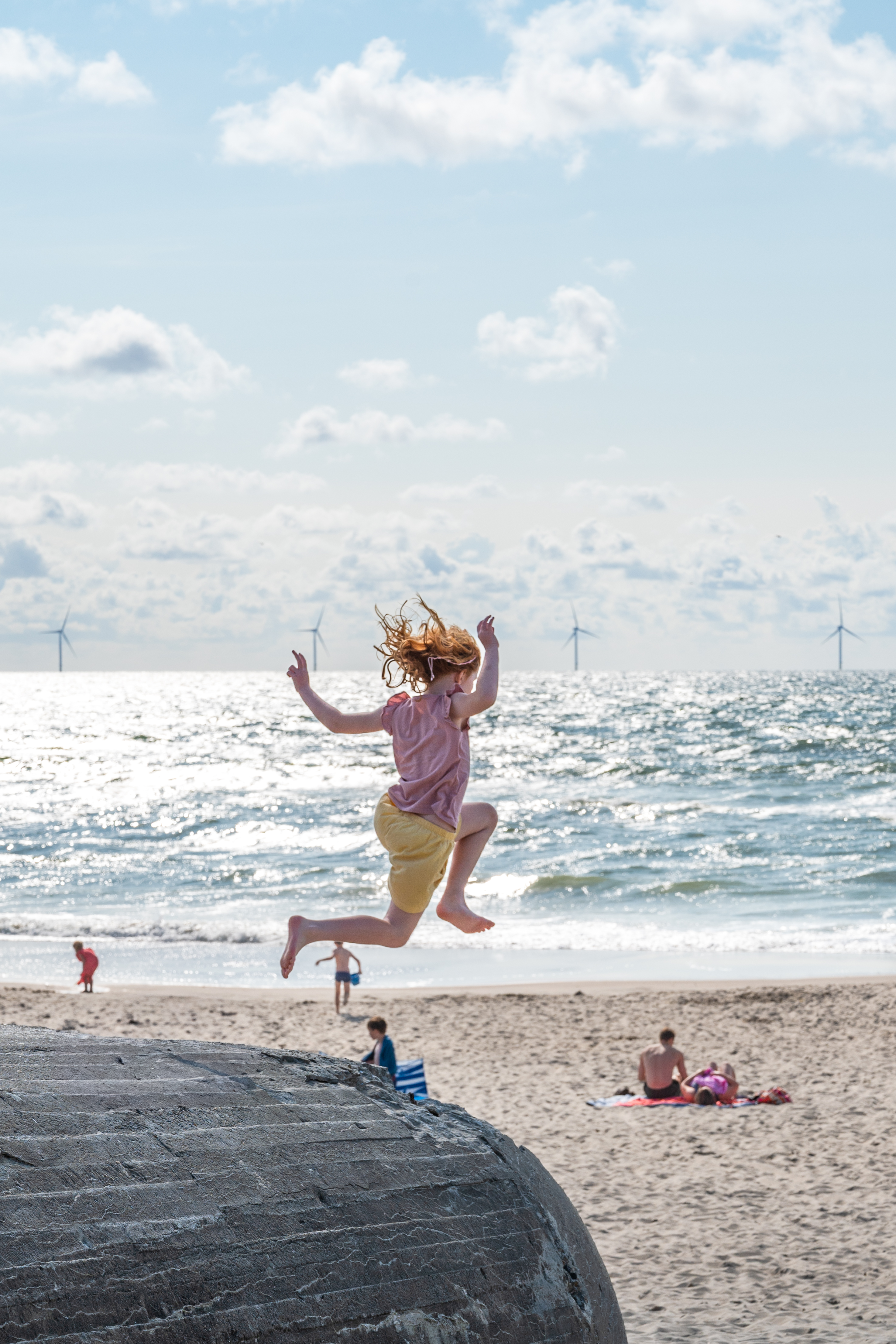Sommer ved vesterhavet. Barn hopper med havet og strand i baggrunden