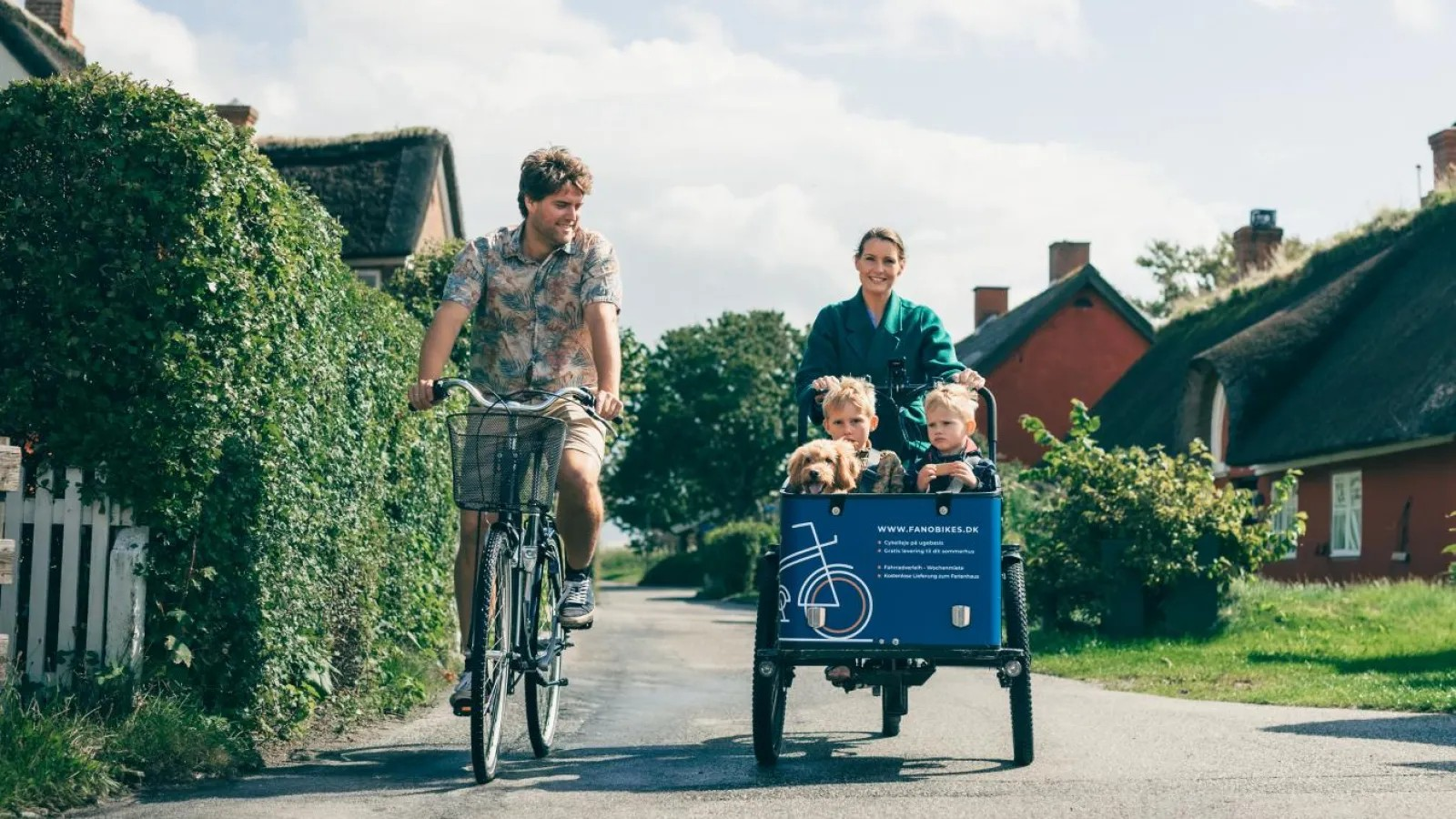Familie på cykeltur gennem en landsby med ladcykel
