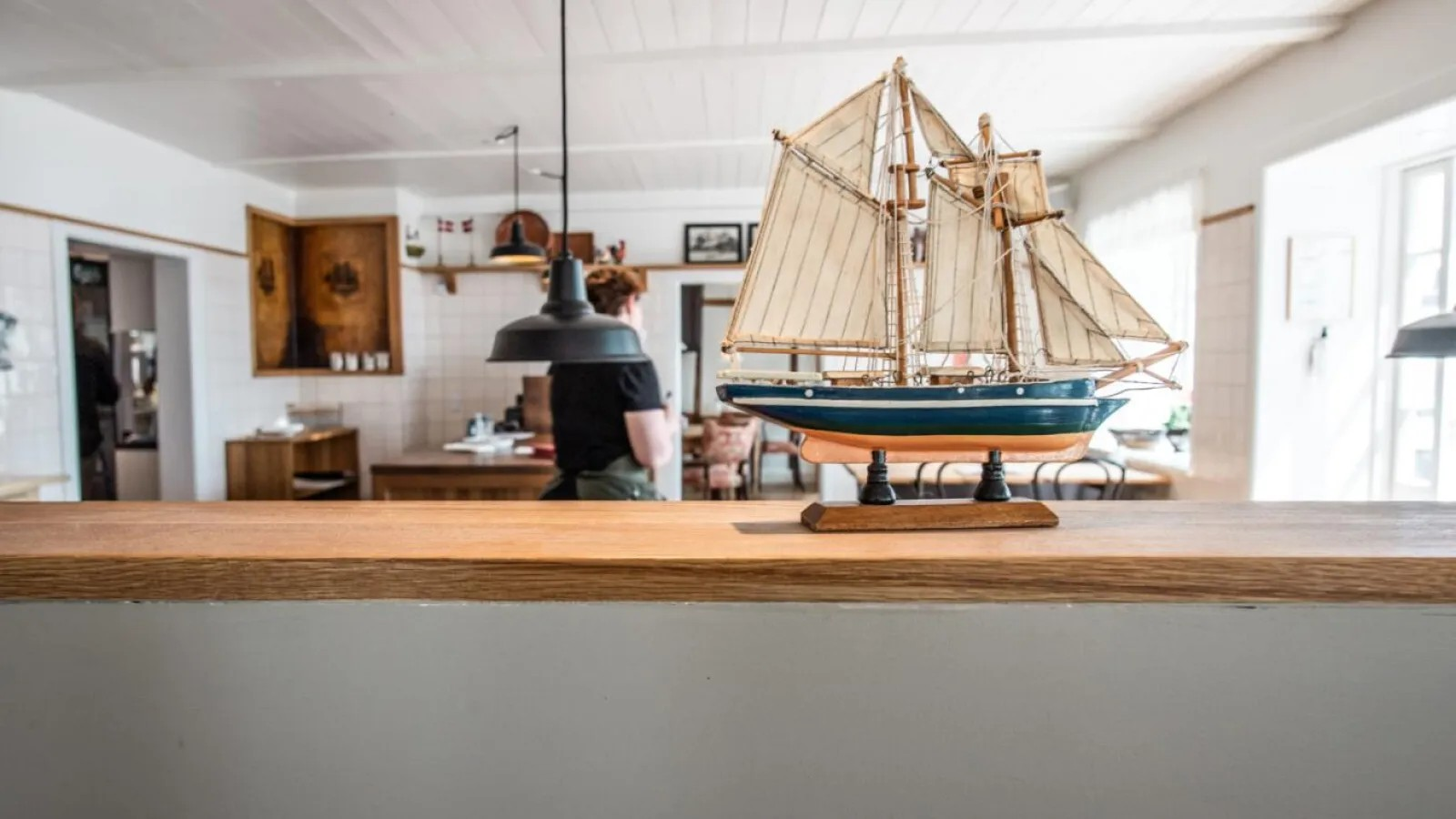 Modelskib i maritimt indrettet rum med person i baggrunden