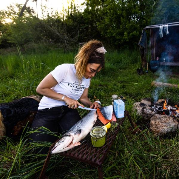 Kvinde tilbereder fisk ved bål