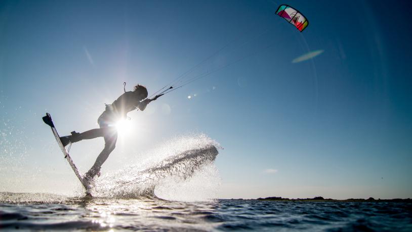 Mand kitesurfer over fjorden