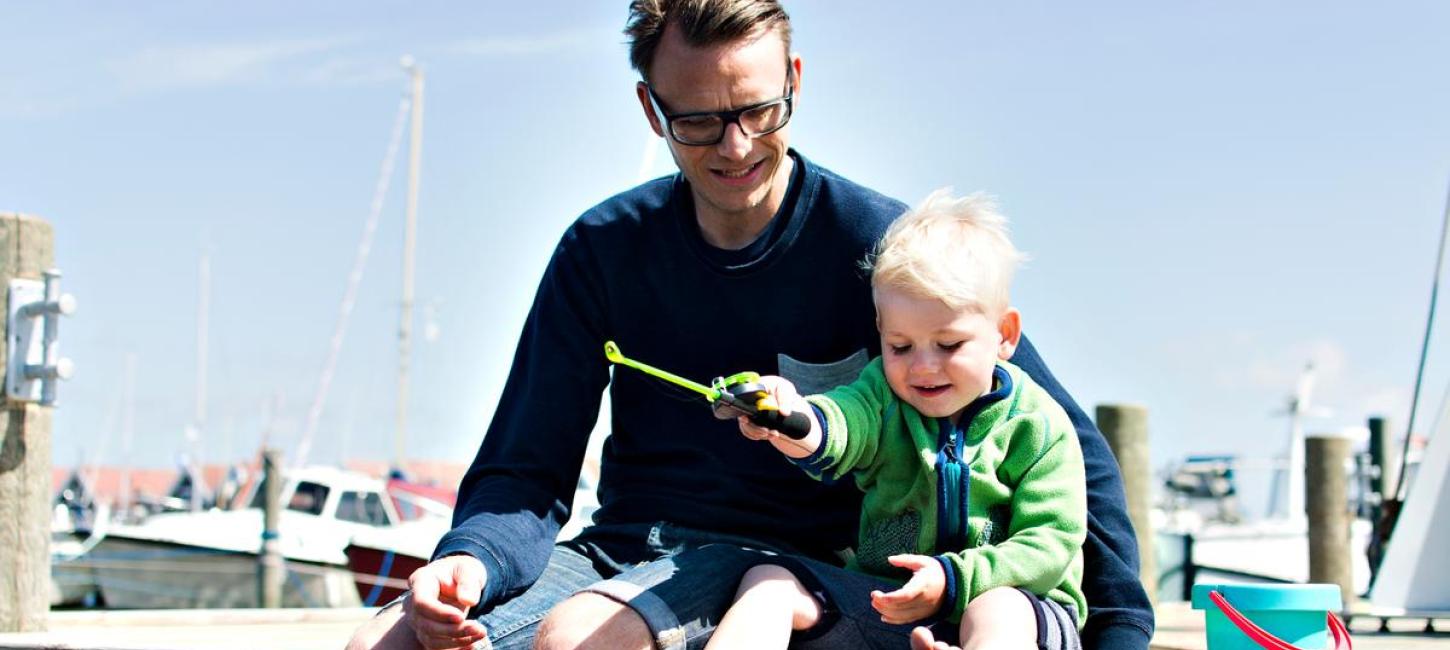 Far og søn sidder på kajen i Bork Havn