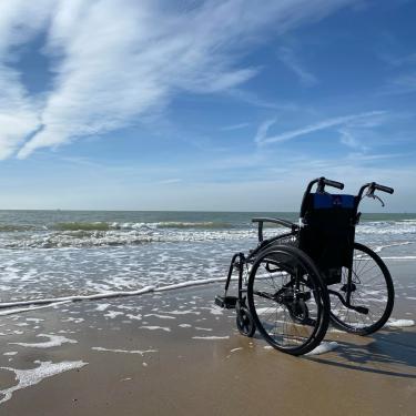 Kørestol på stranden i vandkanten